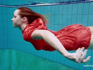 Vermelho longo vestido e grande tetas floating em o piscina