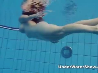 Redheaded vogëlushe duke notuar lakuriq në the pishinë